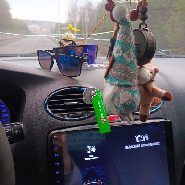 Driver documents cluttered car interior with cracked windshield in Markovo