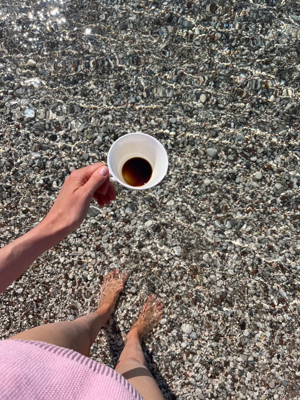 Woman enjoys morning coffee in shallow waters at Budva beach