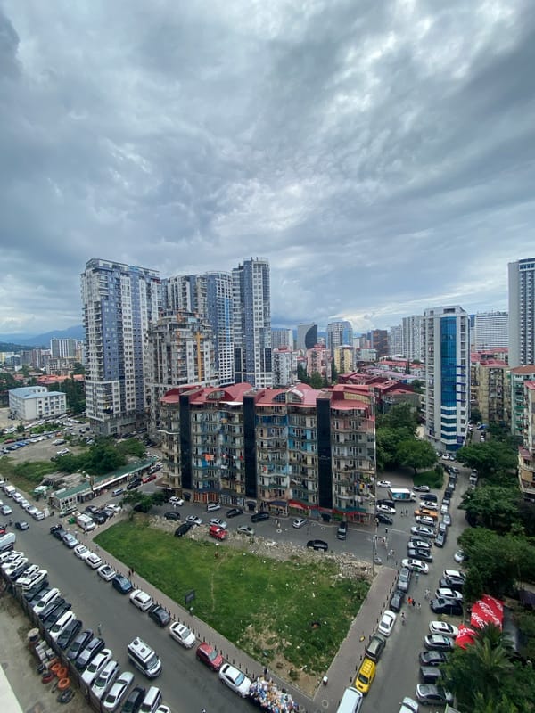 Quiet street lined with parked cars in cloudy Batumi