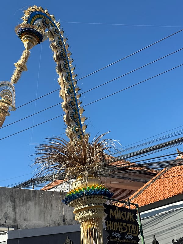 Morning street life in North Kuta, Bali, with a ceremonial penjor