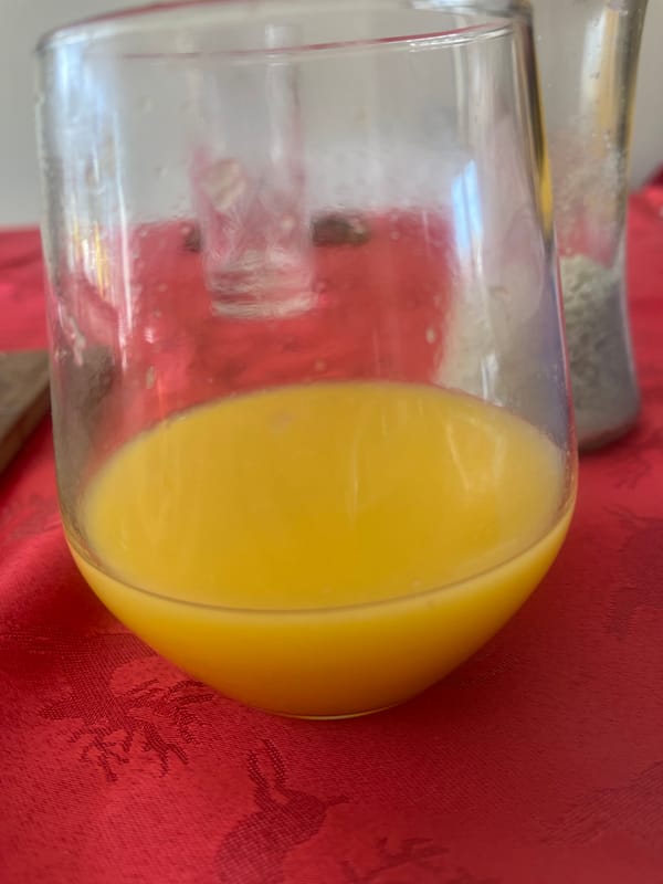 Glass of orange juice spotted on red tablecloth in Maidstone