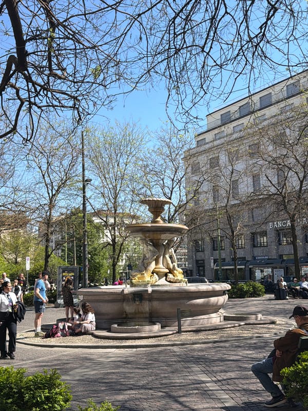 Crowds gather around historic stone fountain in Milan