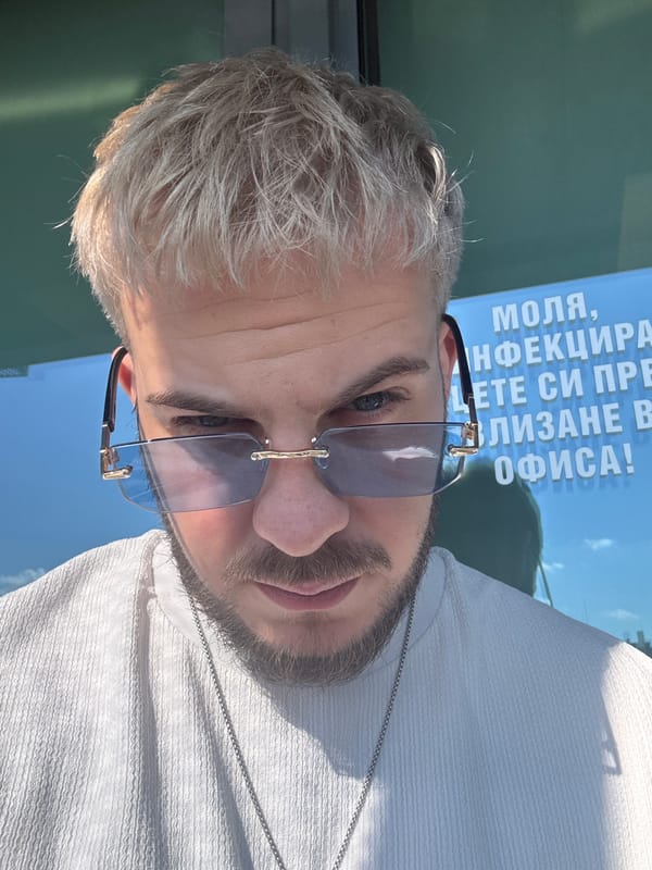Man in sunglasses photographed near Bulgarian poster in Sofia