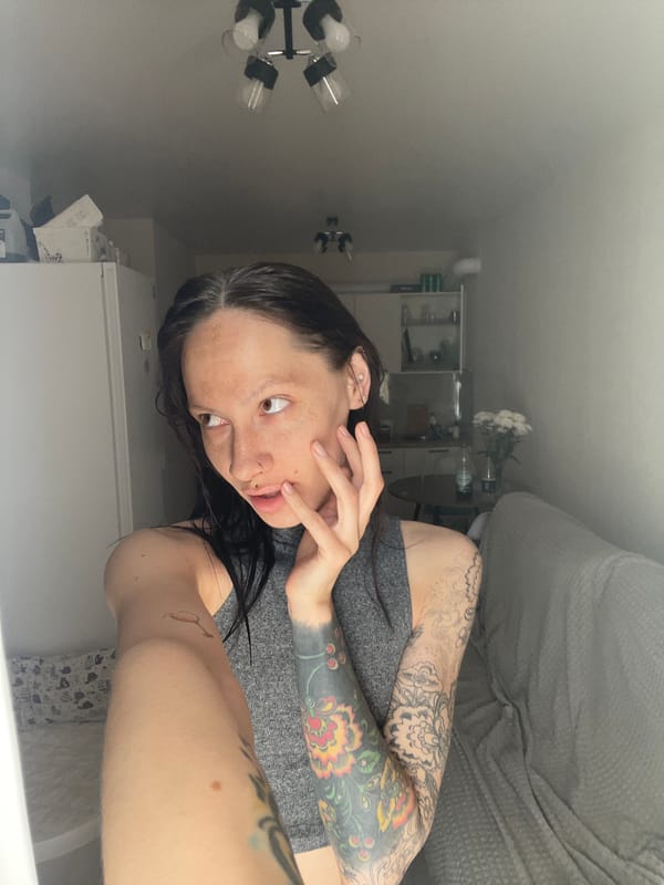 Woman with tattoos observed indoors near furniture