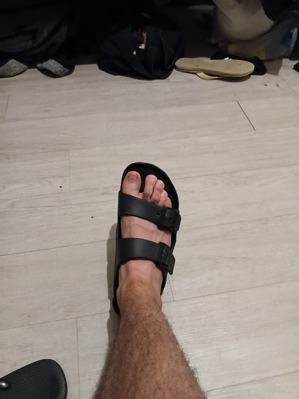 Person in black sandals observed on wooden floor in São Paulo