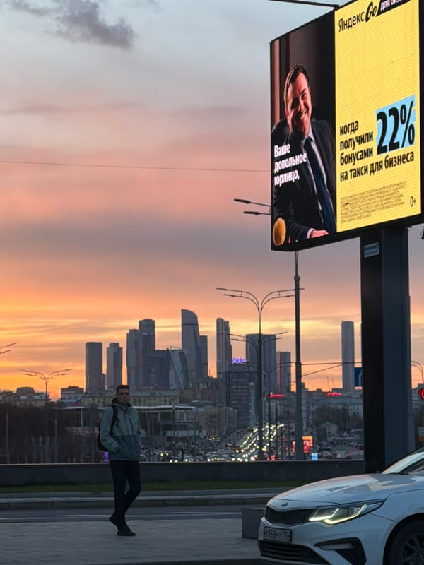 Pedestrian walks Moscow street at sunset near city skyscrapers