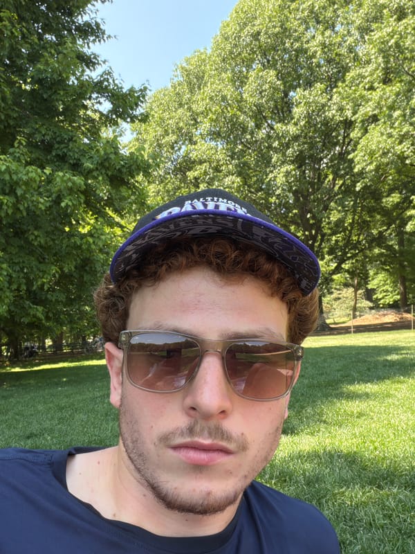 Man rests on lawn wearing Ravens cap in NYC