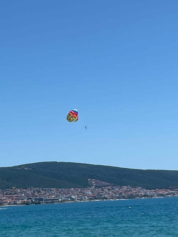 Crowded summer beach day at Nesebar with parasailing overhead