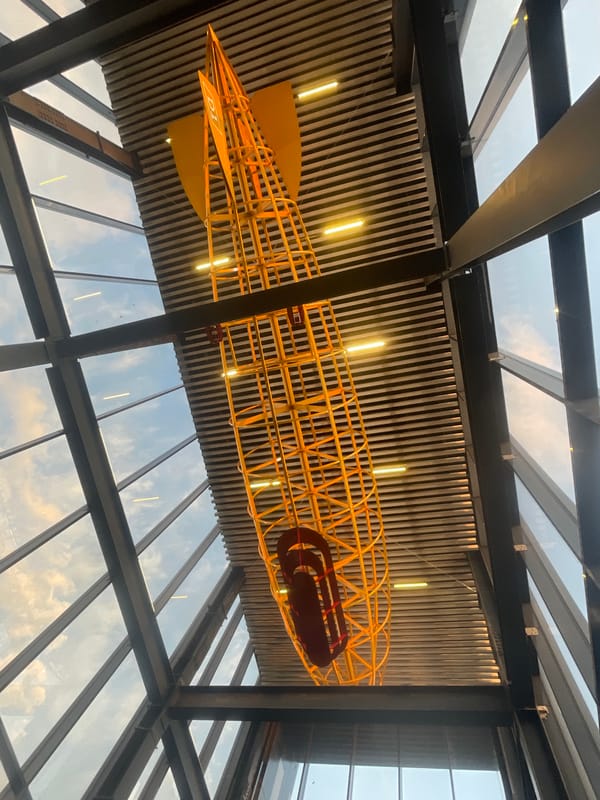 Yellow skeletal airship model displayed in modern building ceiling