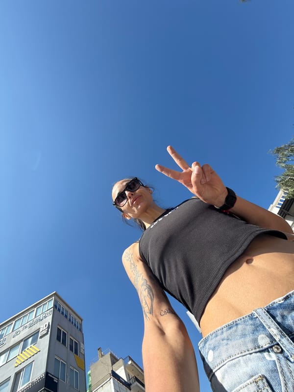 Woman takes selfies on Chania sidewalk making peace sign