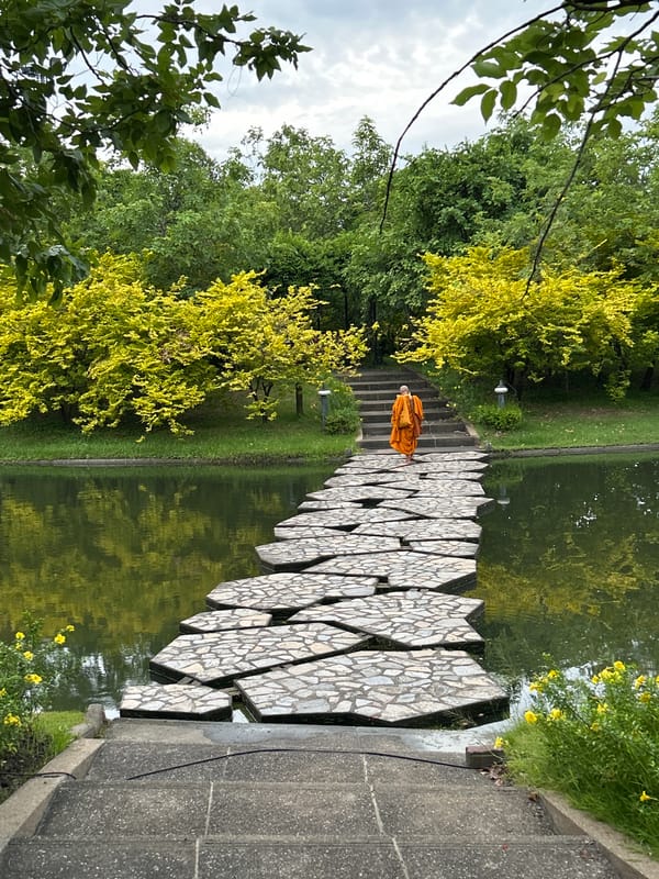 Monk walks stone water path in Bangkok park