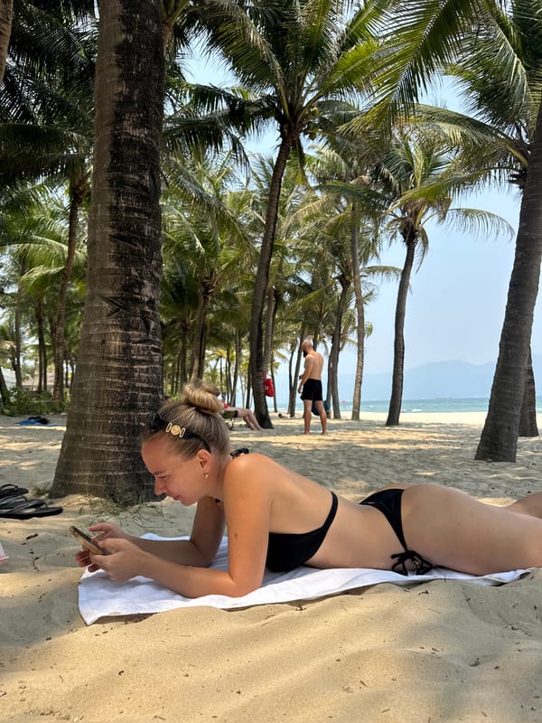 Woman relaxes on phone at palm-lined Đà Nẵng beach