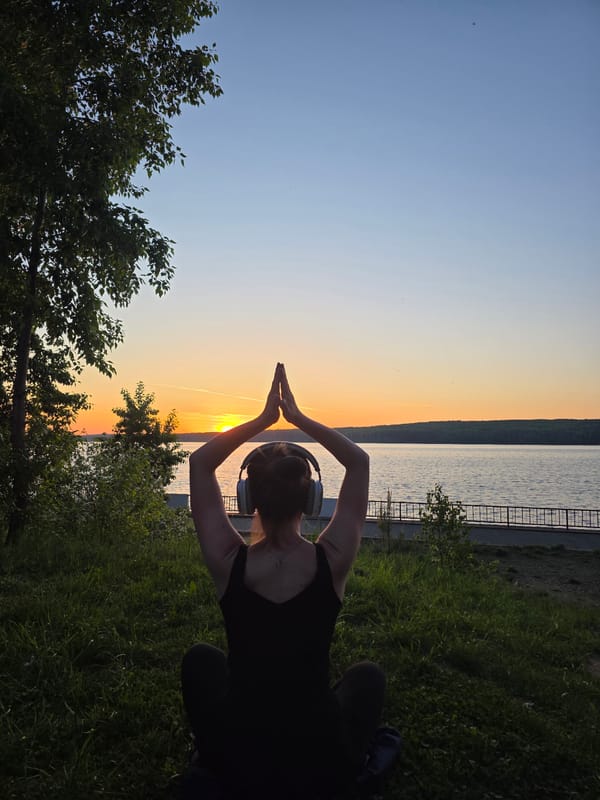 Person practices yoga poses at waterfront during sunset in Russia