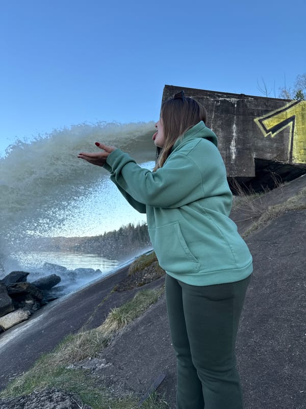 Woman reaches toward waterfall at concrete structure in Russia