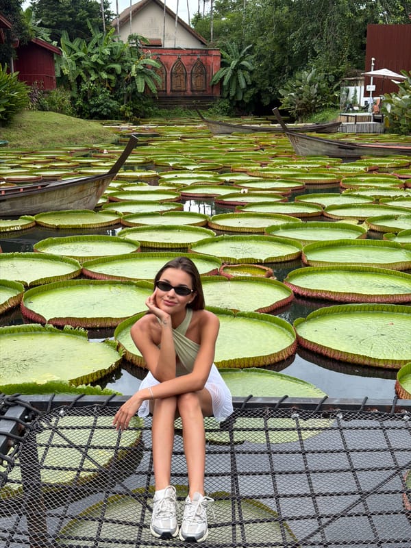 Tourist poses with giant water lilies at Thai cafe