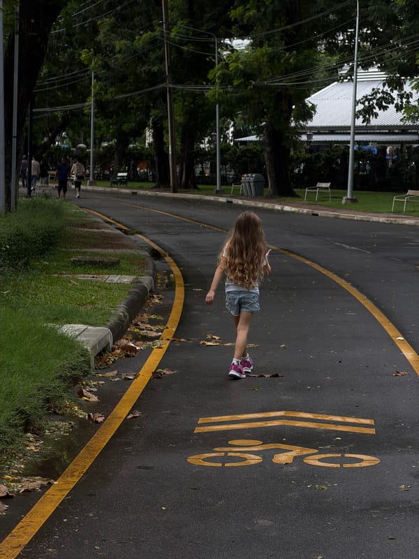 Child walks through Bangkok park on rainy morning