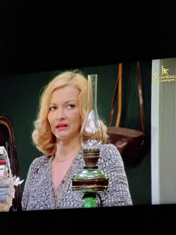 Woman in patterned top observed indoors with ornamental lamp