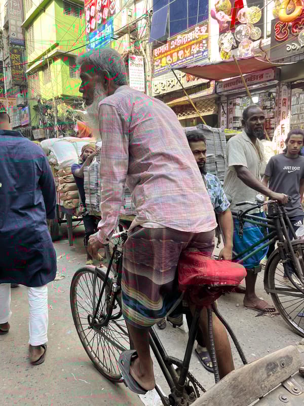 Morning commerce bustles through Dhaka streets with traditional transport