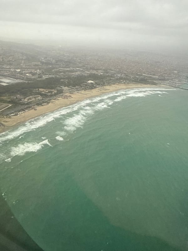 Aerial view captures Catania coastline with waves and cityscape