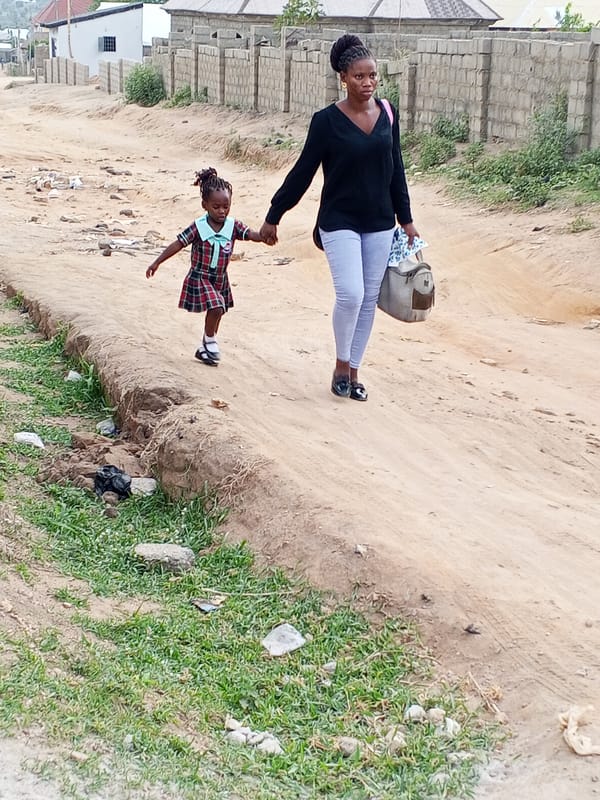 Mother and daughter walk hand-in-hand on urban dirt road