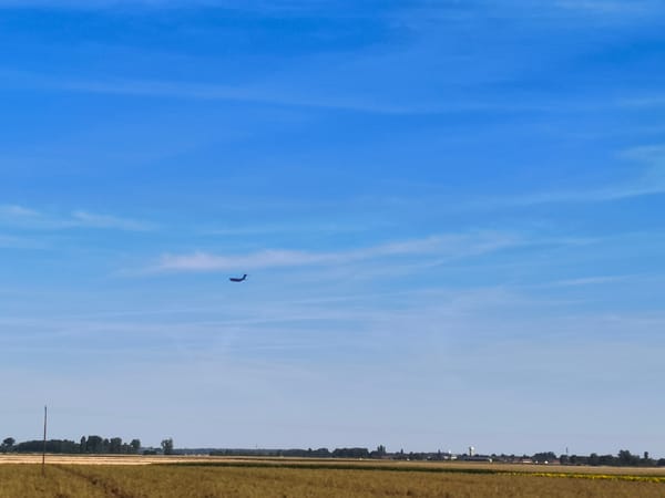 Airplane crosses clear skies over rural French countryside
