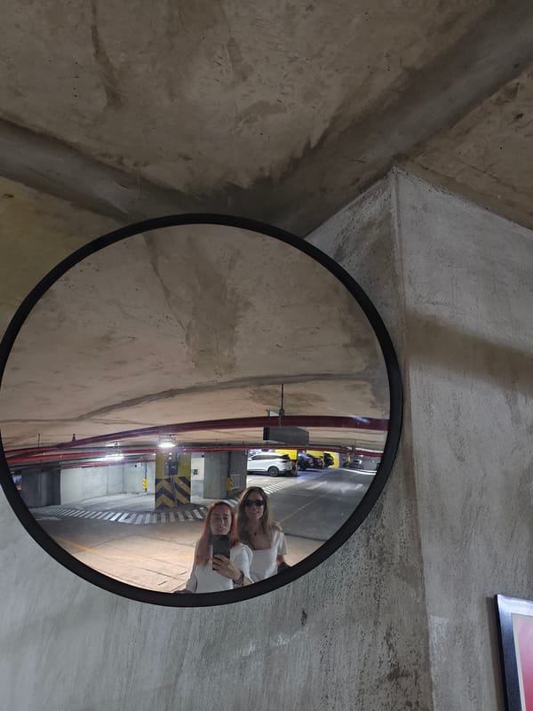 Security mirror reflects parking garage view on concrete wall