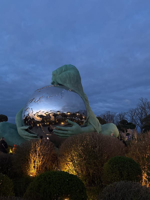 Evening park scene with illuminated statue and light-adorned trees