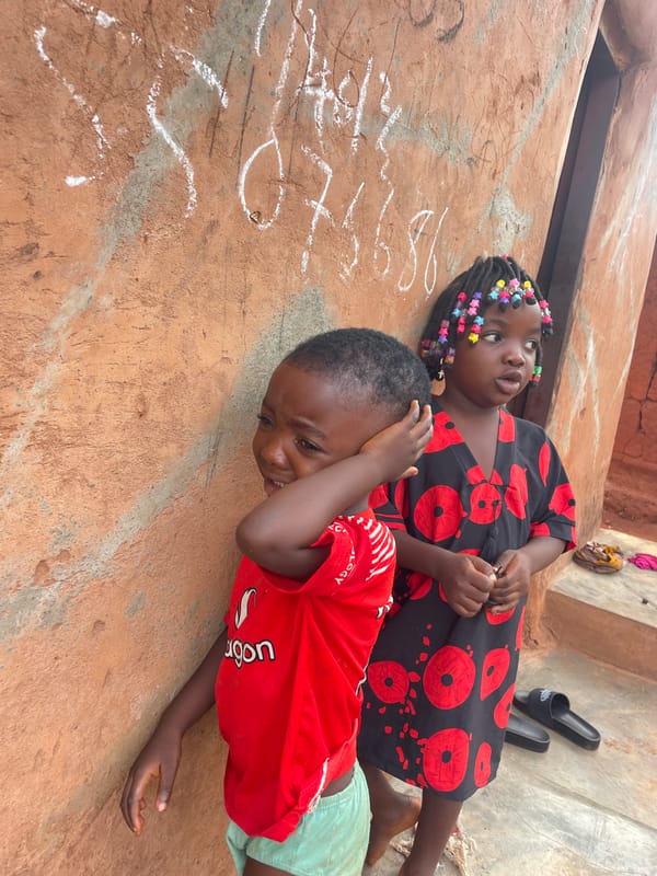 Two children rest on concrete surface in Ogbe, Nigeria