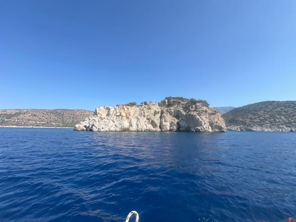 Sailboat underway on open ocean, island and mountains ahead
