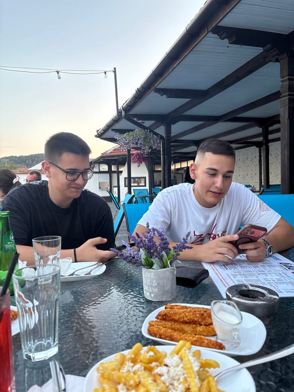 Friend group at a Panagyurishte café, phones out, summer evening