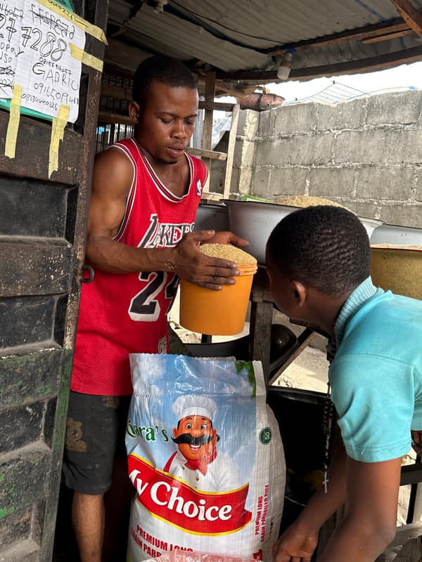 Two men handle rice grains in Ado market stall