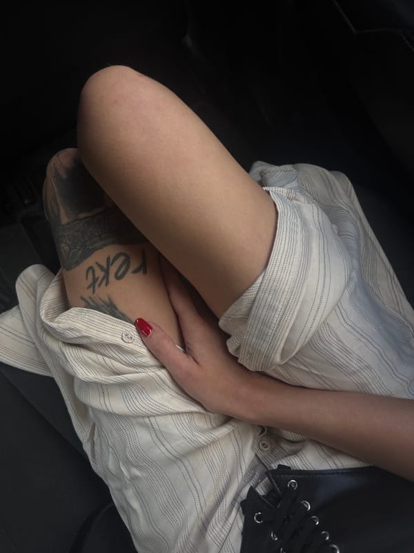 Person with "rekt" tattoo sits cross-legged in Holon