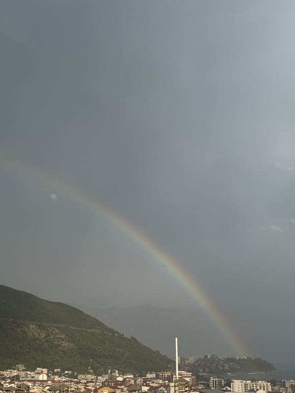 Rainbow over Budva's coastal skyline on a cloudy afternoon