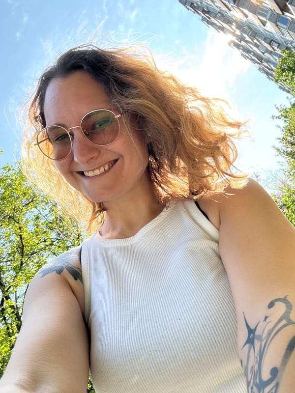 Person in glasses and tank top photographed smiling