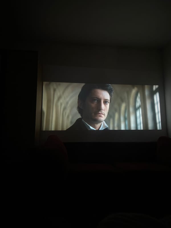 Man's image displayed on screen in darkened Murino room