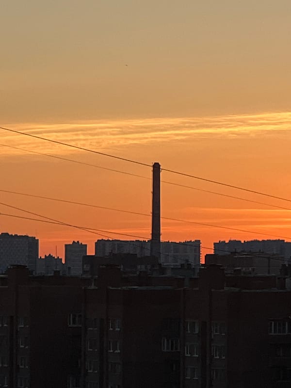 Sinyavino at golden hour: apartment blocks, chimneys, and trams