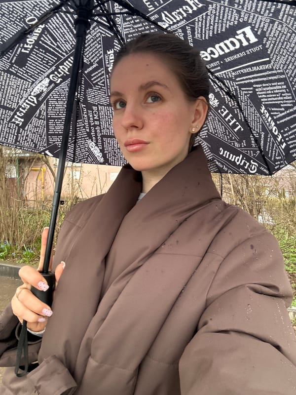 Woman with umbrella, baby in car seat observed in Klin