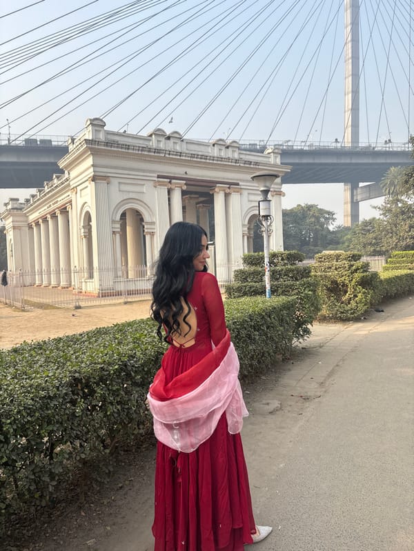 Woman photographed near historic building and bridge in Kolkata