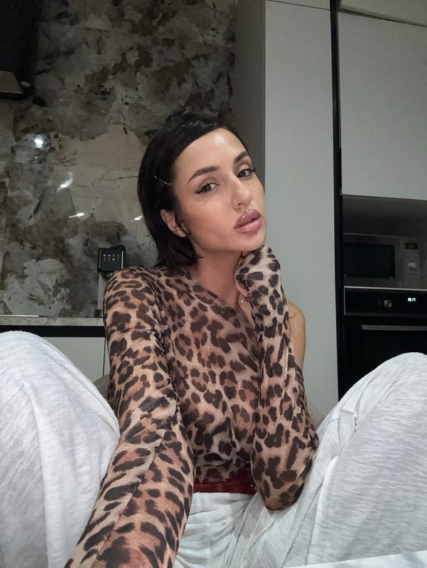 Woman poses in kitchen wearing leopard-print top