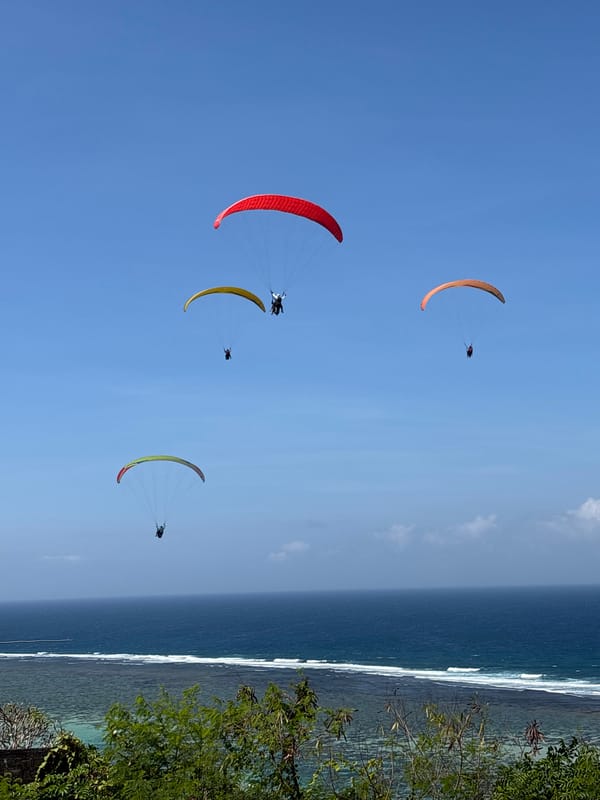 Paragliders fill the sky above Kuta Selatan's clifftop launch site