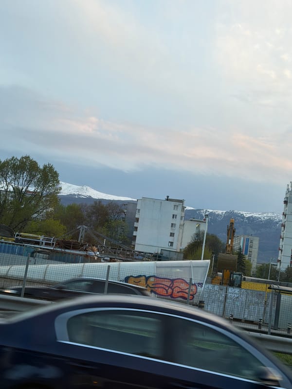Evening urban street scene with snow-capped mountains observed