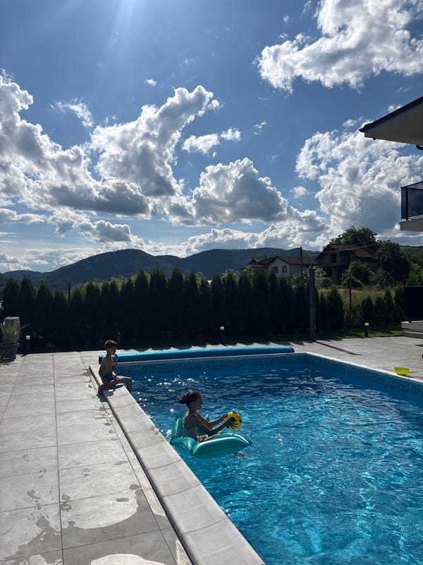 Children play at lakeside pool amid scenic mountain views
