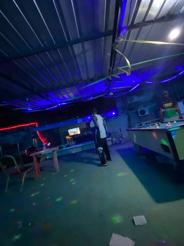 Men play pool at nighttime venue in Ado, Nigeria