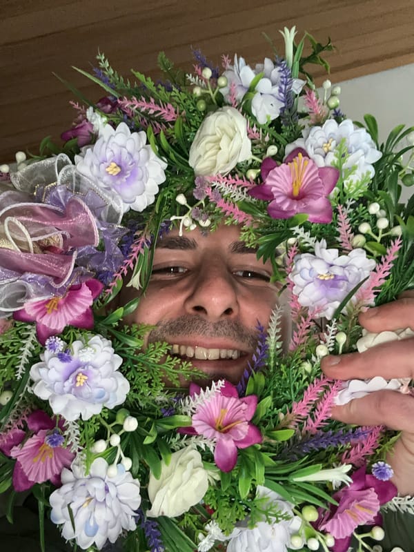 Man poses with floral wreath, candles displayed in Slavyani