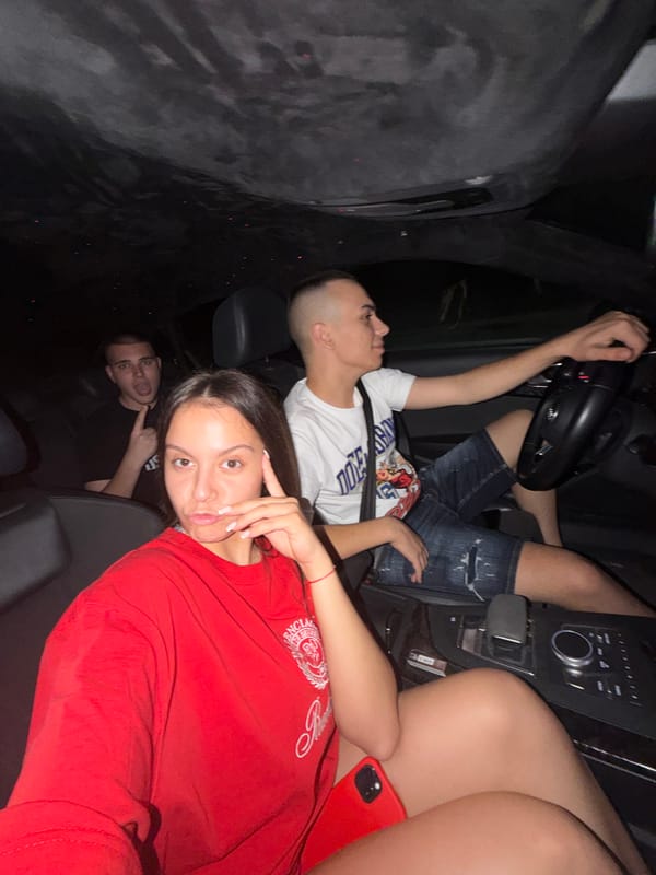 Young woman poses playfully in car at night in Ruse