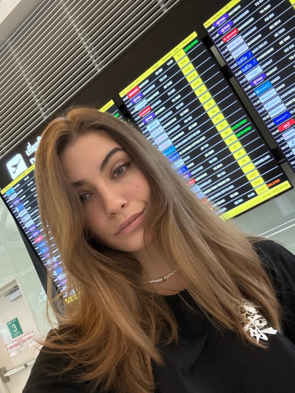 Woman poses at airport departure board in Thailand