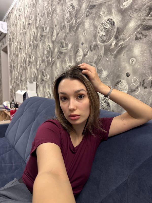 Woman takes selfie on blue couch in maroon shirt