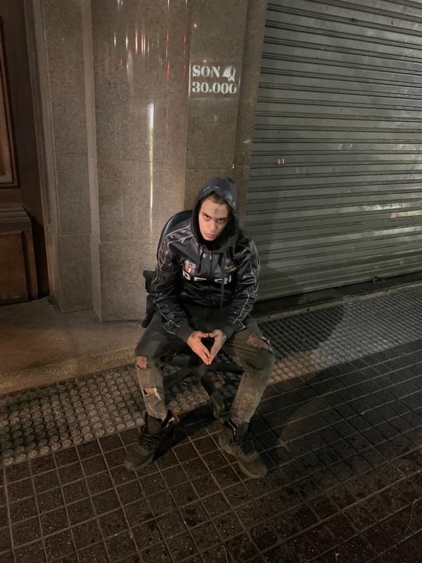 Person sits on Buenos Aires street near illuminated Obelisk