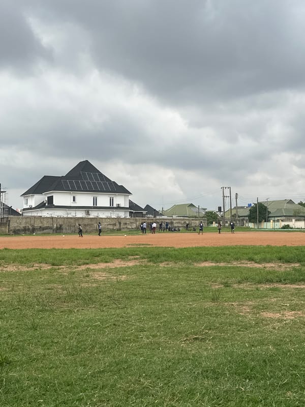 Informal soccer session on a dusty Abuja field, mid-afternoon.