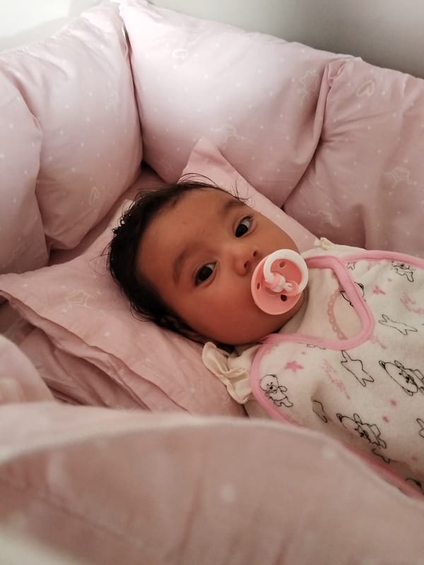 Baby rests in pink star bedding wearing white sleeper